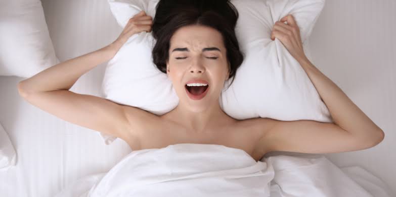 Woman having a screaming orgasm on white bed