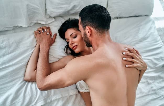 Man on top of woman in intimate best position for anal sex on a white bed